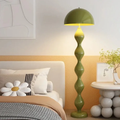 Green floor lamp in a bedroom setting with a bed and side table.
