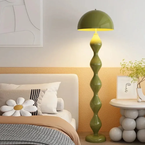 Green floor lamp in a bedroom setting with a bed and side table.