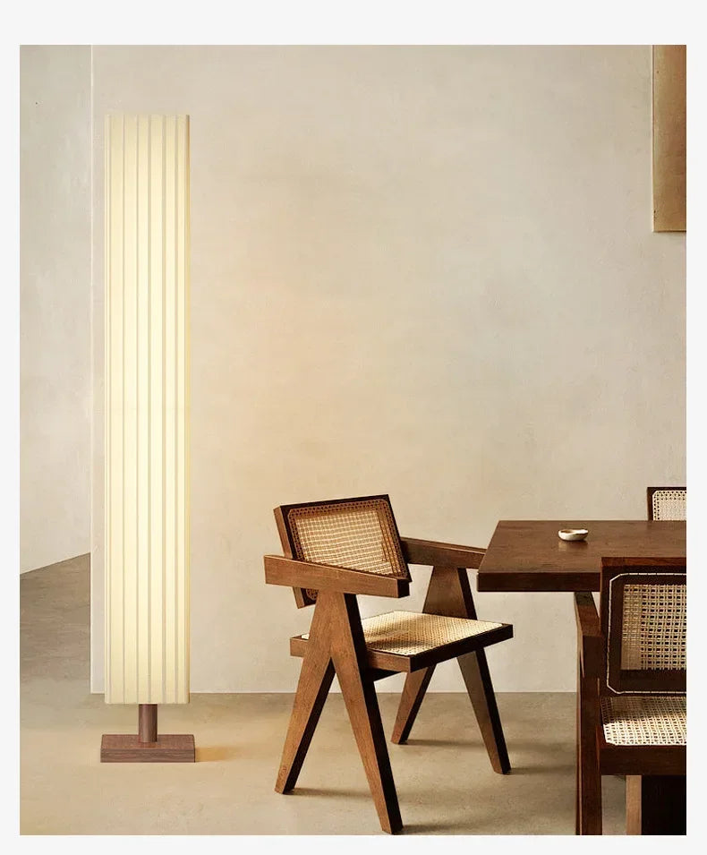 Wooden chair and table with a tall floor lamp in a room setting.