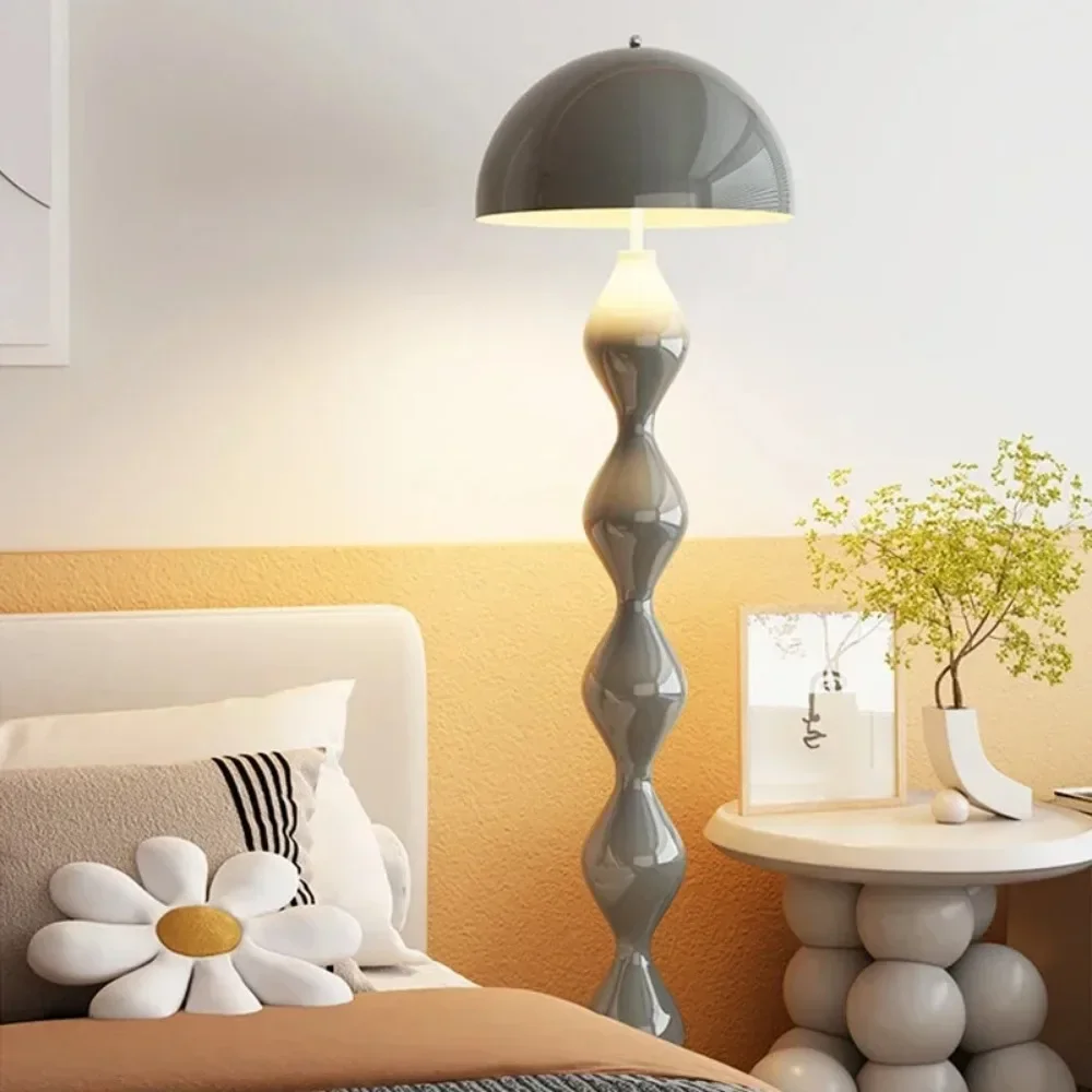 Gray floor lamp in a bedroom setting with a bed and side table.