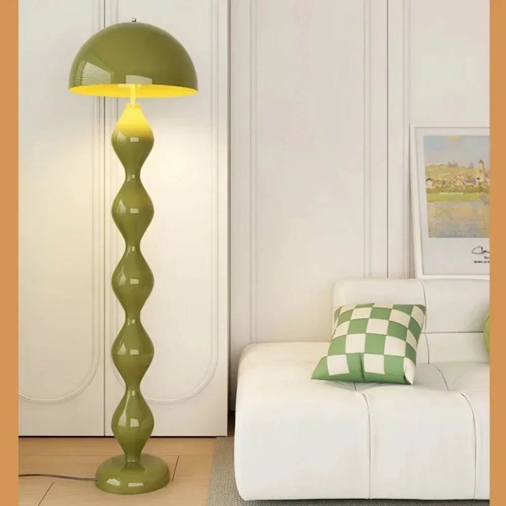 Green floor lamp next to a white sofa with a green and white checkered pillow in a room.