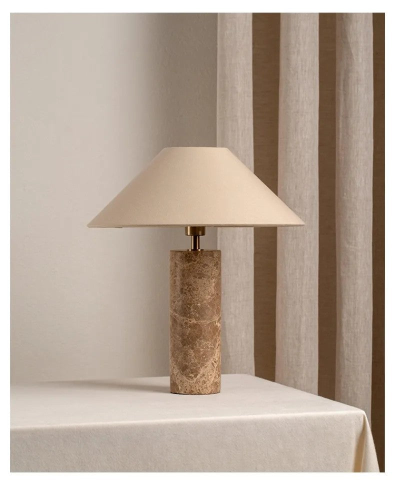 Marble able lamp with a textured base on a tablecloth-covered table against striped curtains.