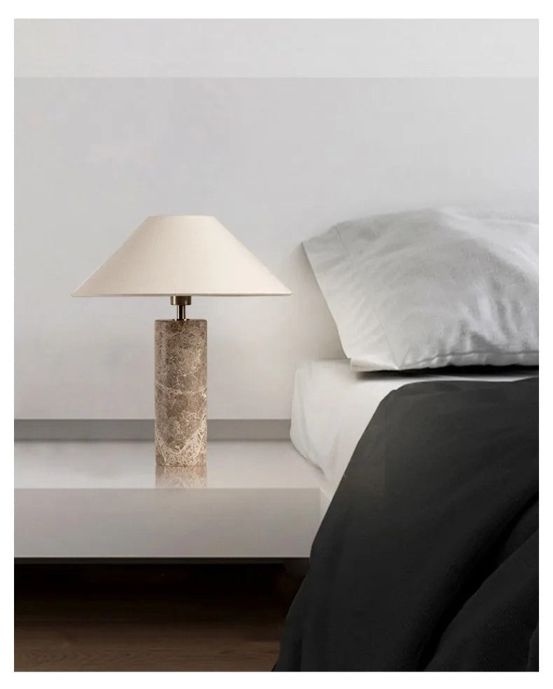 Table lamp on a nightstand next to a bed with pillows.