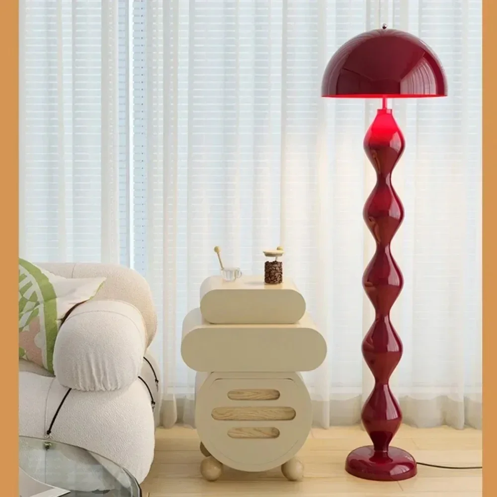 Red floor lamp in a living room setting with a sofa and side table.