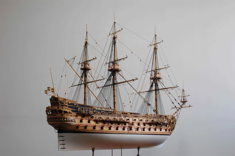 Model of a three-masted sailing ship on a gray background