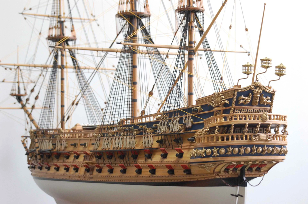 Close-up of a model ship with detailed architecture and rigging against a light background